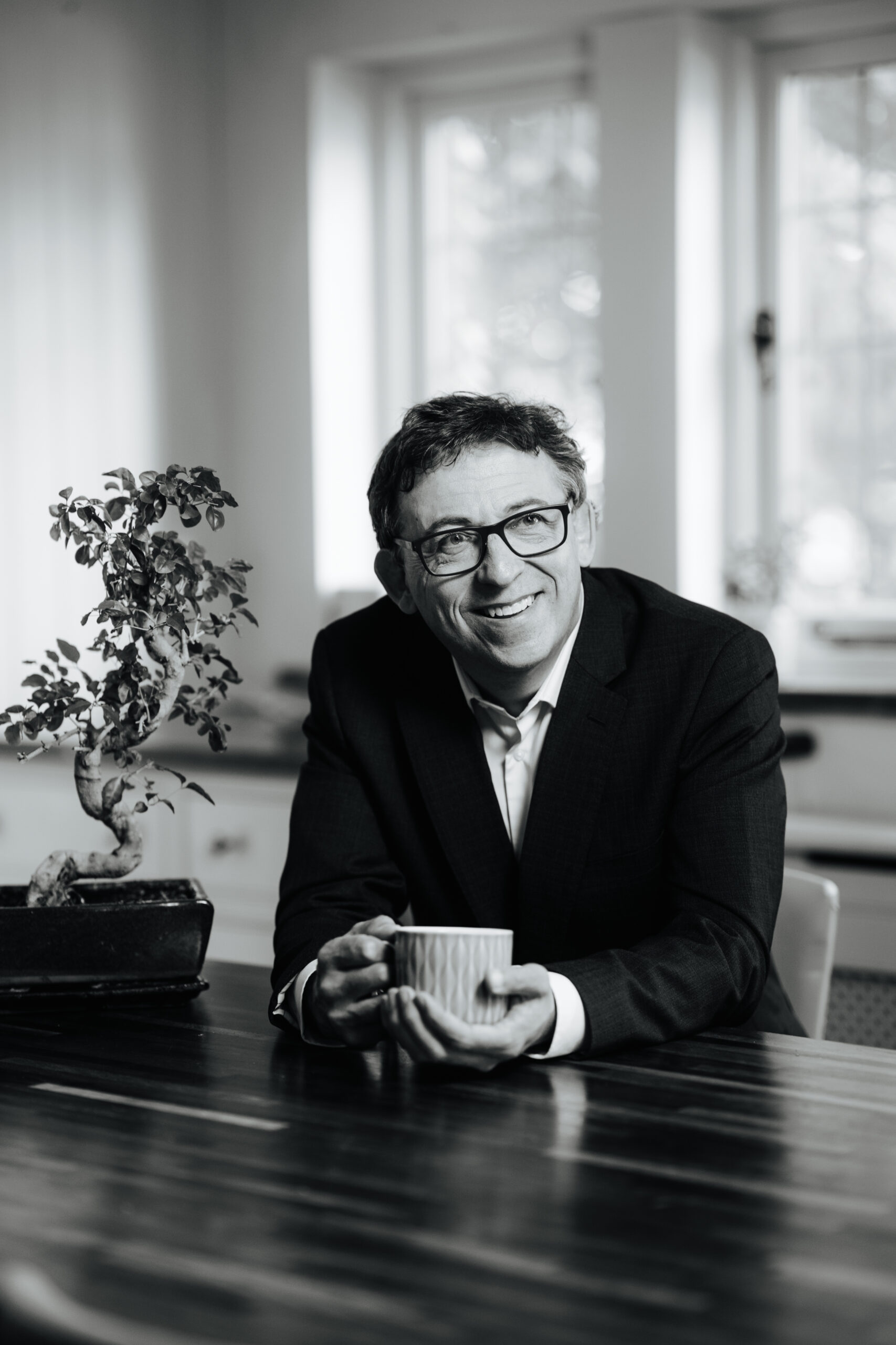 A picture of Will Todd at a desk with a plant to his left